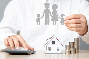 Wall Mural - Businessman using a calculator is calculating the cost of building a house and hand hold the family of paper art in the office, The saving money for house or real estate owner in the future concept.