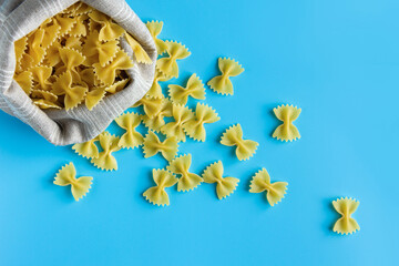 Wall Mural - Raw pasta farfalle with copy space on blue background