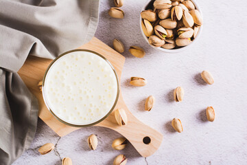 Wall Mural - Lactose-free pistachio milk in a glass and nuts on the table top view