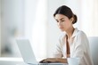 © Iryna - Focused and attractive young woman uses a laptop, combining technology with a professional atmosphere.