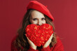 © Alliance - happy modern woman in red sweater and beret with red heart