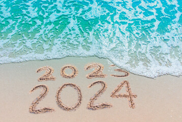 Wall Mural - message year replaced by 2023 2024 written on beach sand background. good bye 2023 hello to 2024 hap