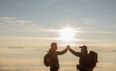 Wall Mural - Two hikers celebrating success in sunrise mist mountains, accomplish with arms up outstretched. beautiful inspirational landscape view,