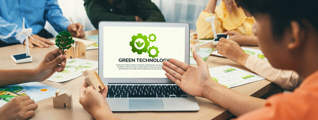 Green technology logo displayed on green business laptop while business team presenting green design to customer. ESG environment social governance and Eco conservative concept. Closeup. Delineation