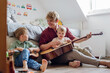 © Halfpoint - Father teaching boys to play on guitar. Boys having fun in their room with dad, playing guitar and singing together. Concept of Father's Day, and fatherly love.