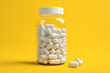 white pills in a bottle on yellow background
