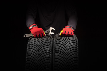 Car tire service and hands of mechanic holding new tyre on black background with copy space for text