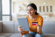 © Prostock-studio - Online Shopping Concept. Smiling Indian Woman Using Digital Tablet And Credit Card