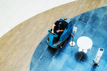 Scrubber dryer-dryer in a commercial building. Washing floors in a large room with a marble surface. Top down view.