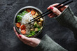© Westend61 - Hands of woman eating bowl of vegan Tomkhakaisoup with tofu, tomatoes, salad, rice noodles, sesame seeds and scallion