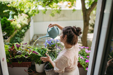 Woman Watering Flowers, Taking Care Of Plants On Balcony