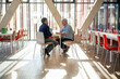 © Westend61 - Businessman discussing with colleague at table in cafeteria