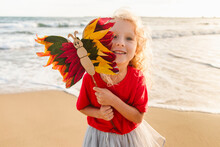 Smiling Girl Holding Multi Colored Butterfly At Beach