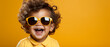 Sonniges Kind: Baby mit großer Sonnenbrille auf gelbem Hintergrund