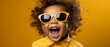 Fröhliches Babyportrait: Dunkle Hautfarbe und gelbe Sonnenbrille