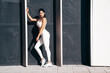 © halayalex - Fitness woman in sports clothing. Sexy young beautiful model athlete doing fitness workout. Female making exercises in street. Stretching out before training. Posing near urban wall
