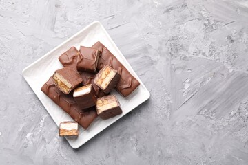 Wall Mural - Tasty chocolate bars with nougat on gray textured table, top view. Space for text