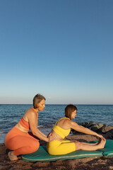 Wall Mural - Yoga instructor with a student practice yoga on the beach