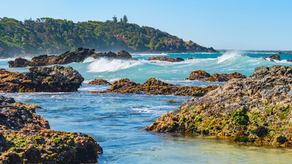 Wall Mural - Australian coast with volcanic rocks at the shore, view from the beach to the horizon with blue water with waves on a summer sunny day.