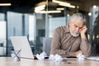 © Liubomir - Upset frustrated gray haired boss sitting inside office at workplace, mature man old businessman in shirt working with laptop, unhappy with company achievement results and negative reports.