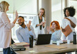 © Luis - Multiethnic business colleagues smiling and celebrating success while working in the office.