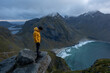© Noah - Man in yellow jacket at Kvalvika Beach at sunset in Lofoten, Norway in the Arctic Circle.  One of Norway's most beautiful beaches. with tower cliffs and large waves.