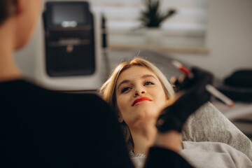 Wall Mural - Young woman undergoing procedure of permanent lip makeup in tattoo salon, closeup