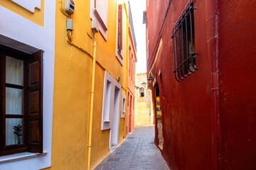 Wall Mural - Traditional narrow paved alley between multicolor building. Chania Old Town, Crete island, Greece.