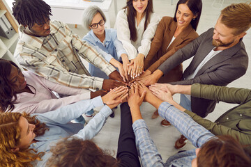 Top view photo of diverse business people men and women putting their arms together. Stack of hands of a group of multiethnic company employees. The concept of unity, partnership and teamwork.