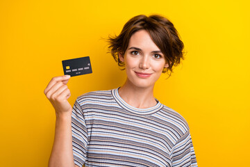 Wall Mural - Portrait of satisfied intelligent adorable girl wear grey t-shirt demonstrate plastic card in hand isolated on yellow color background