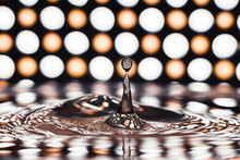 Water Drop Creating A Splash Against A Backdrop Of Bokeh Lights