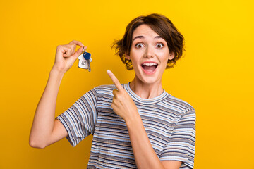 Sticker - Photo of excited cheerful cute girl dressed trendy clothes demonstrate keys purchase property isolated on yellow color background