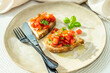 Homemade bruschetta with toast, garlic, olive oil, fresh cherry tomatoes and basil, on a beige ceramic plate, with black fork and knife. Vegetarian food, eating healthy,  home cooking. Italian dish 