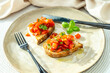 Homemade bruschetta with toast, garlic, olive oil, fresh cherry tomatoes and basil, on a beige ceramic plate, with black fork and knife. Vegetarian food, eating healthy,  home cooking. Italian dish 