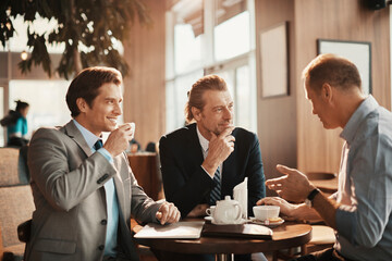 Wall Mural - Businessmen Engaged in Discussion Over Coffee