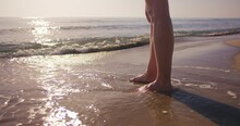 Close-up Shot Of Legs Woman Stand On Sea Beach At Sunset, Low Angle Shot