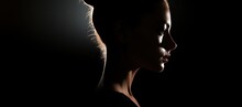  A Woman's Profile In The Dark With Her Hair Pulled Back And Her Face Slightly Turned To The Side.