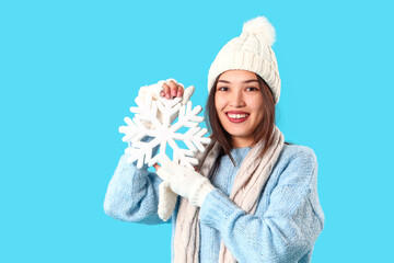 Sticker - Young Asian woman in winter clothes with snowflake on blue background