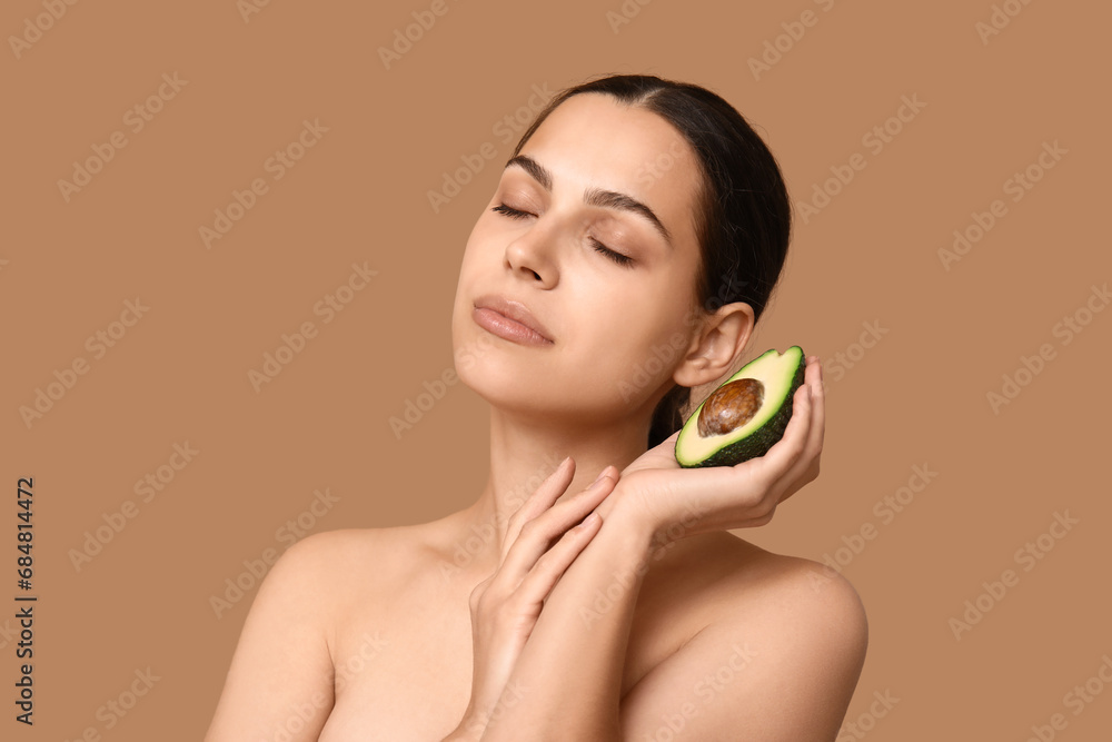 Pretty young woman with fresh avocado on beige background