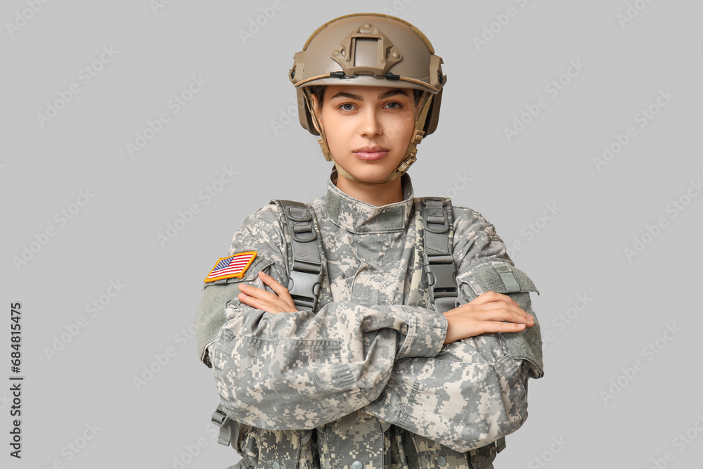 Confident young female soldier in uniform on grey background