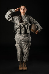 Wall Mural - Confident young woman in military uniform saluting on black background