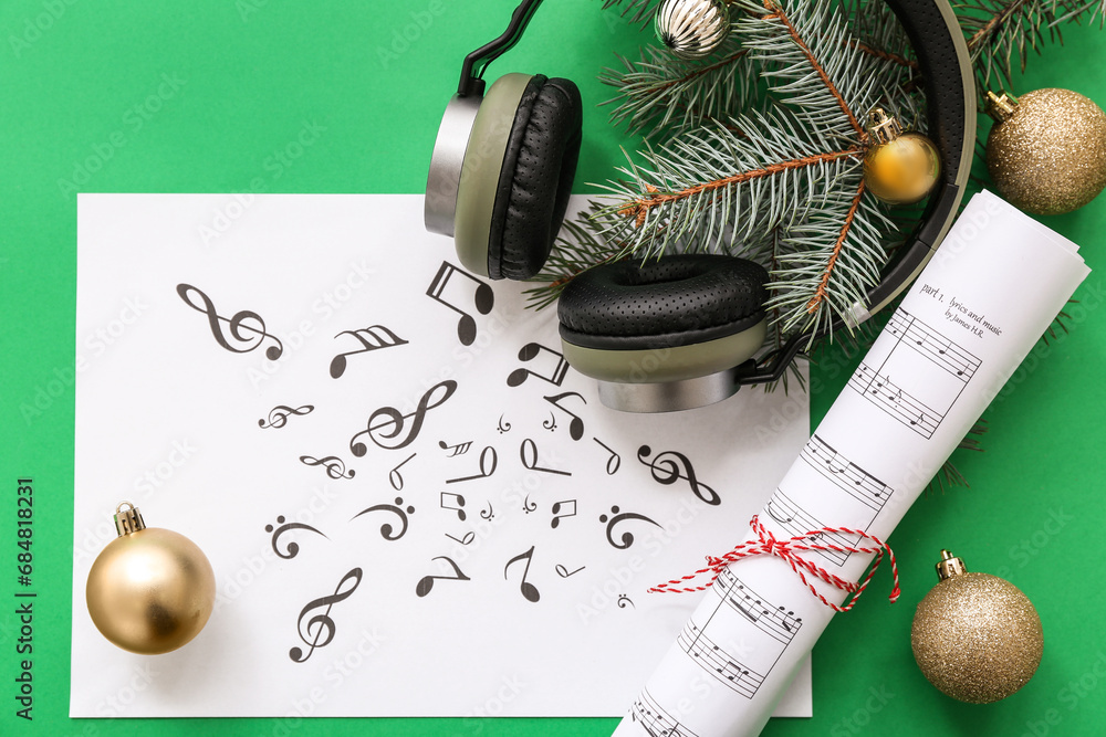 Music note sheets with headphones and Christmas decor on green background