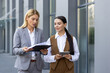 © Liubomir - Young female director and female assistant secretary are walking outside the office center and talking. Documents, agreement, work are discussed, interviews are conducted.