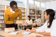© JackF - Polite friendly african american librarian helping woman find necessary information, giving her books..