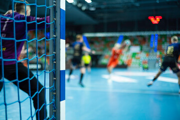 Wall Mural - Detail of handball goal post with net and handball match in the background.