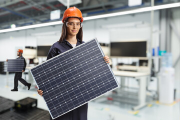 Wall Mural - Solar panel production line, female worker in a factory holding a photovoltaic panel