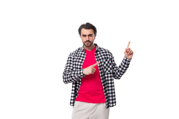 Wall Mural - young handsome european brutal guy with gorgeous hair and beard points with his hand on a white background with copy space