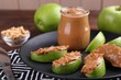 Slices of fresh green apple with peanut butter on table, closeup
