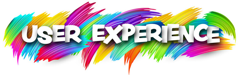 User experience paper word sign with colorful spectrum paint brush strokes over white.