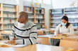 © JackF - Portrait of young adult man wearing mask for viral protection studying in at public library